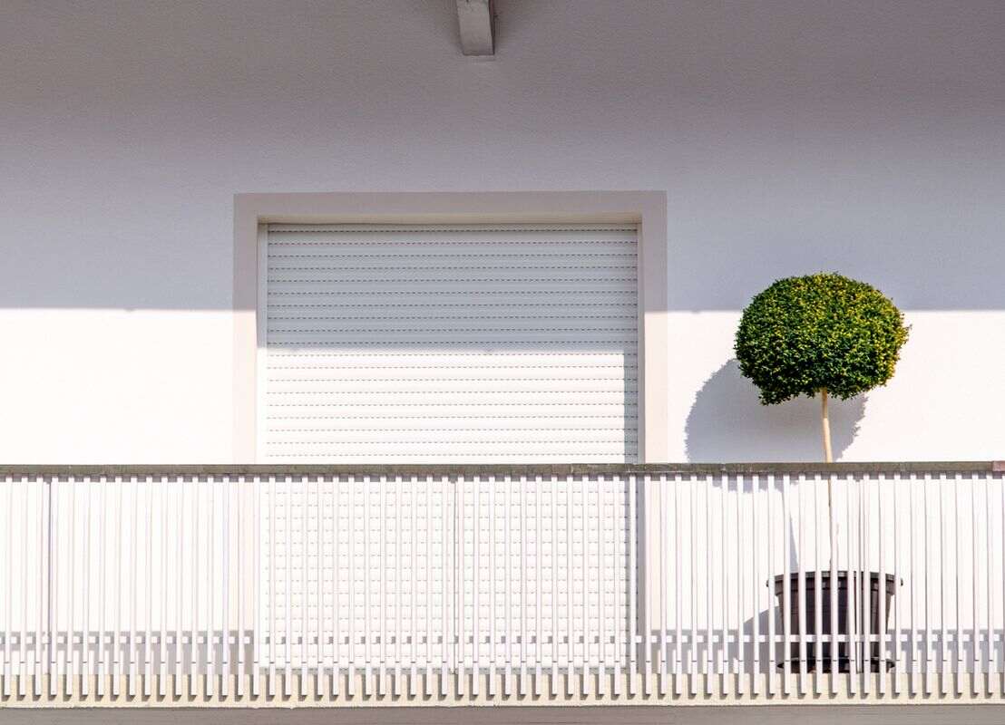 Volet roulant PVC blanc avec plante sur le balcon